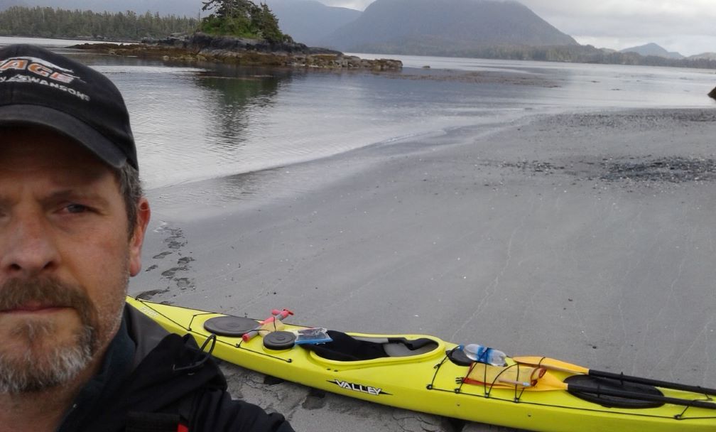 Sitka Sunshine Kayaks guide on the beach with his Valley sea kayak in Sitka, Alaska